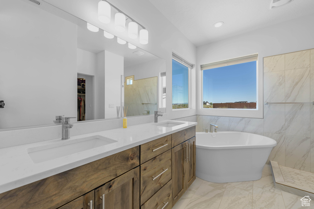 Bathroom with vanity, tile walls, and separate shower and tub