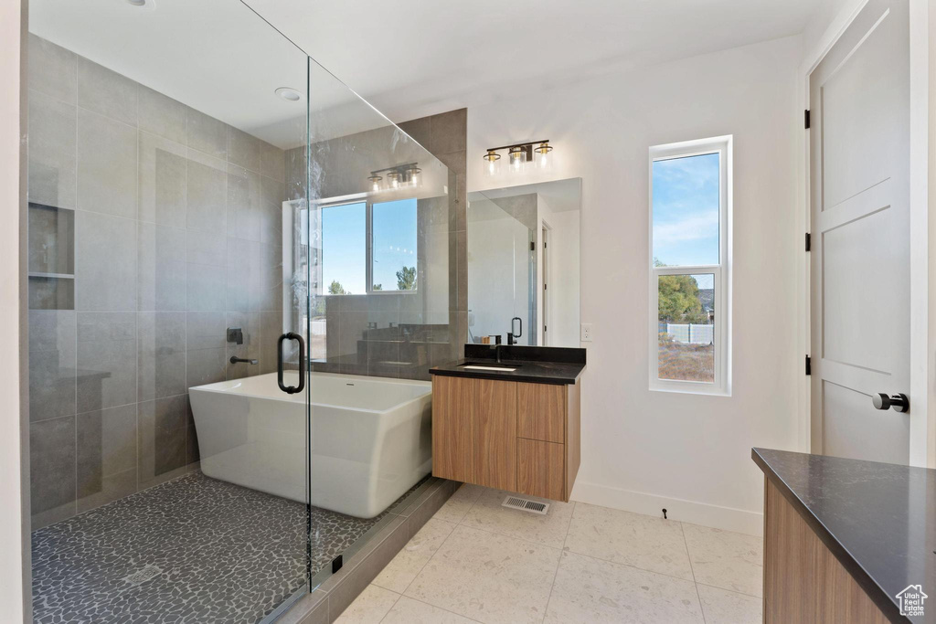 Bathroom featuring a wealth of natural light, vanity, shower with separate bathtub, and tile patterned flooring