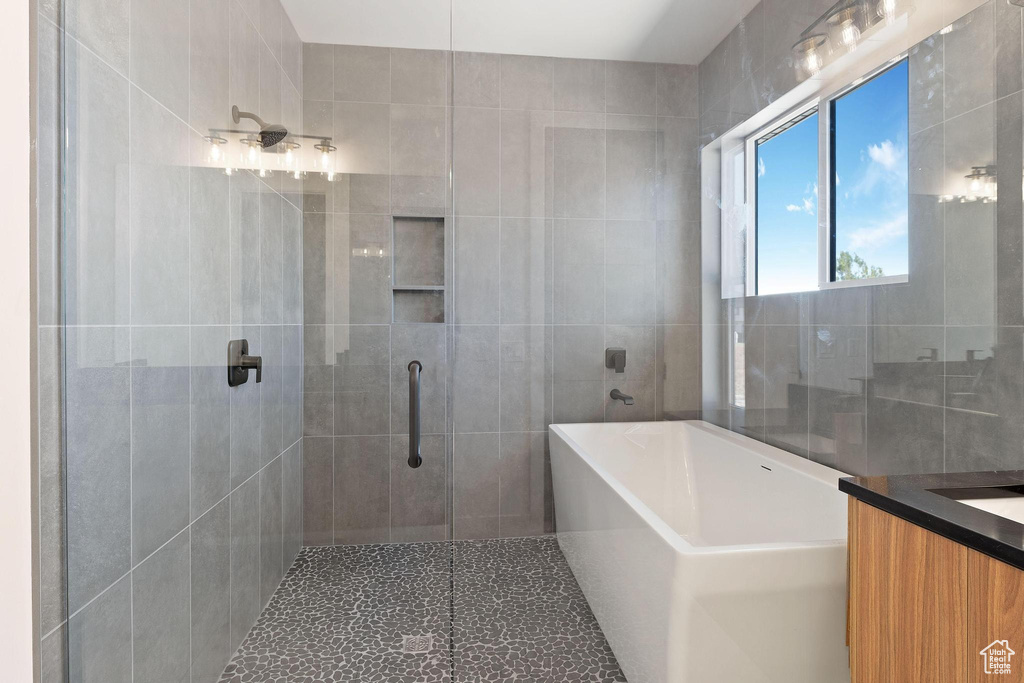 Bathroom with tile walls, vanity, and plus walk in shower