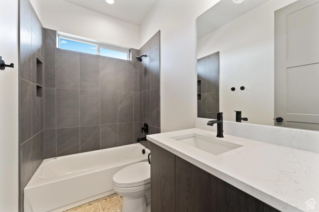 Full bathroom with vanity, tiled shower / bath, and toilet
