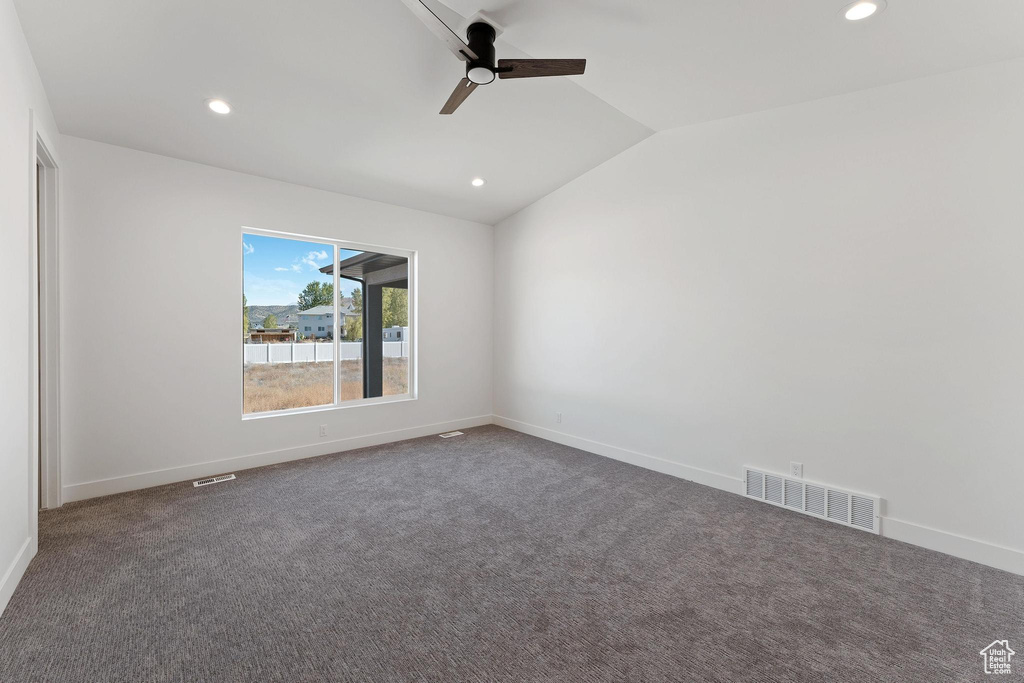 Unfurnished room featuring lofted ceiling, ceiling fan, and dark colored carpet