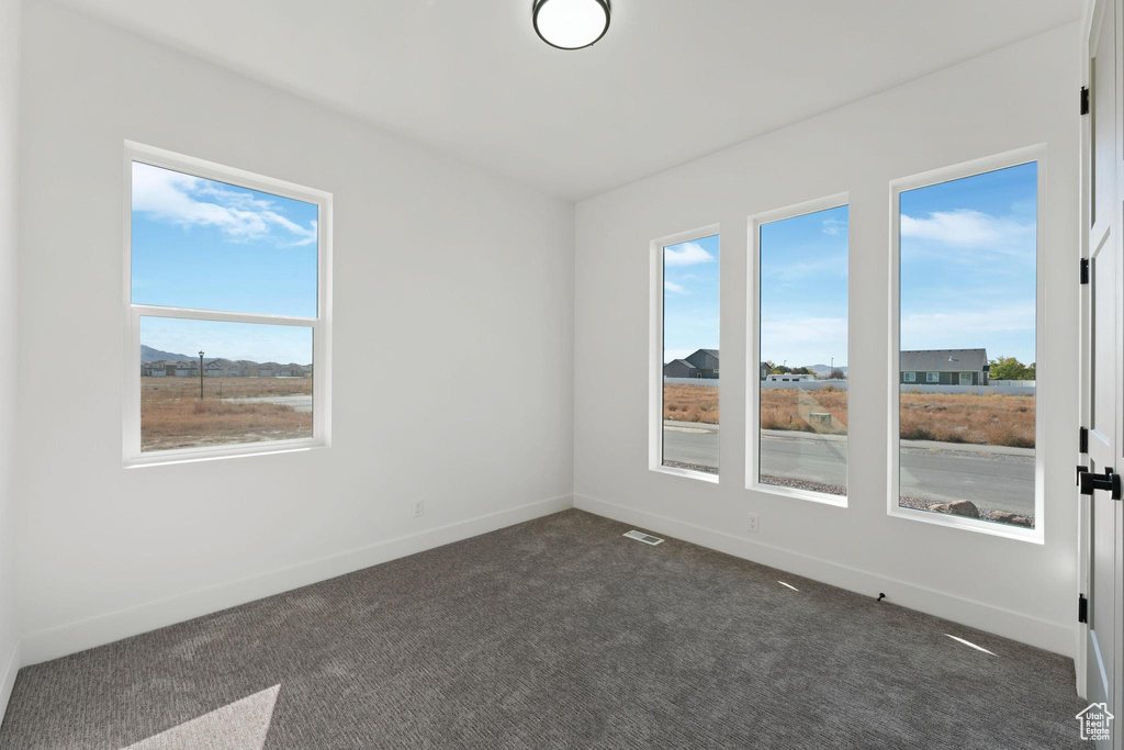 Unfurnished room with plenty of natural light and dark carpet