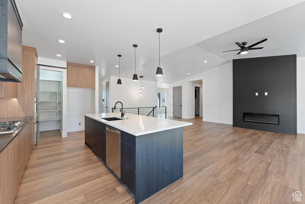 Kitchen featuring light hardwood / wood-style flooring, hanging light fixtures, a large island, sink, and vaulted ceiling