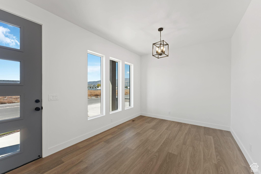 Unfurnished dining area featuring a notable chandelier and hardwood / wood-style flooring
