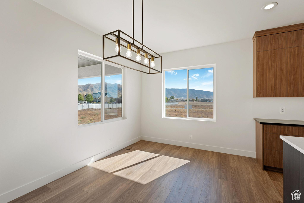 Unfurnished dining area featuring a mountain view, wood-type flooring, and an inviting chandelier