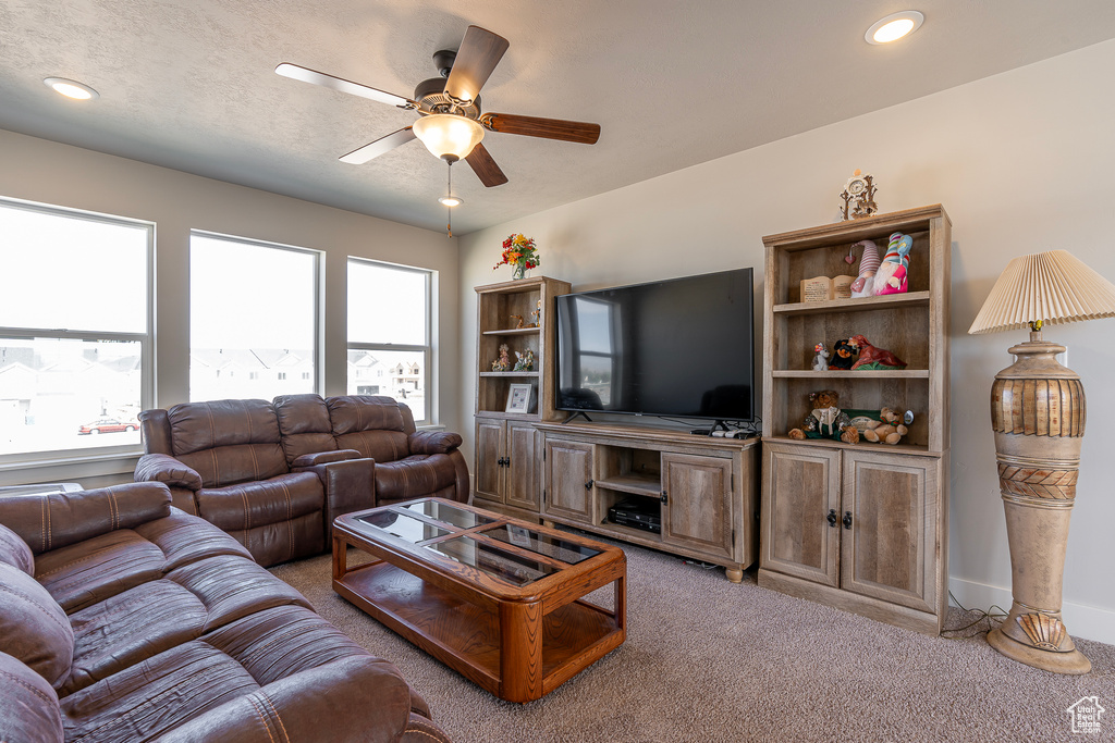 Living room featuring ceiling fan, light carpet, and a textured ceiling