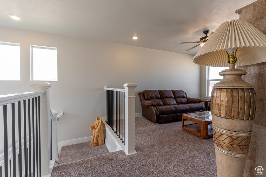 Carpeted living room with ceiling fan and plenty of natural light