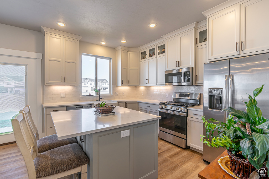 Kitchen featuring tasteful backsplash, a center island, a breakfast bar area, stainless steel appliances, and light hardwood / wood-style flooring