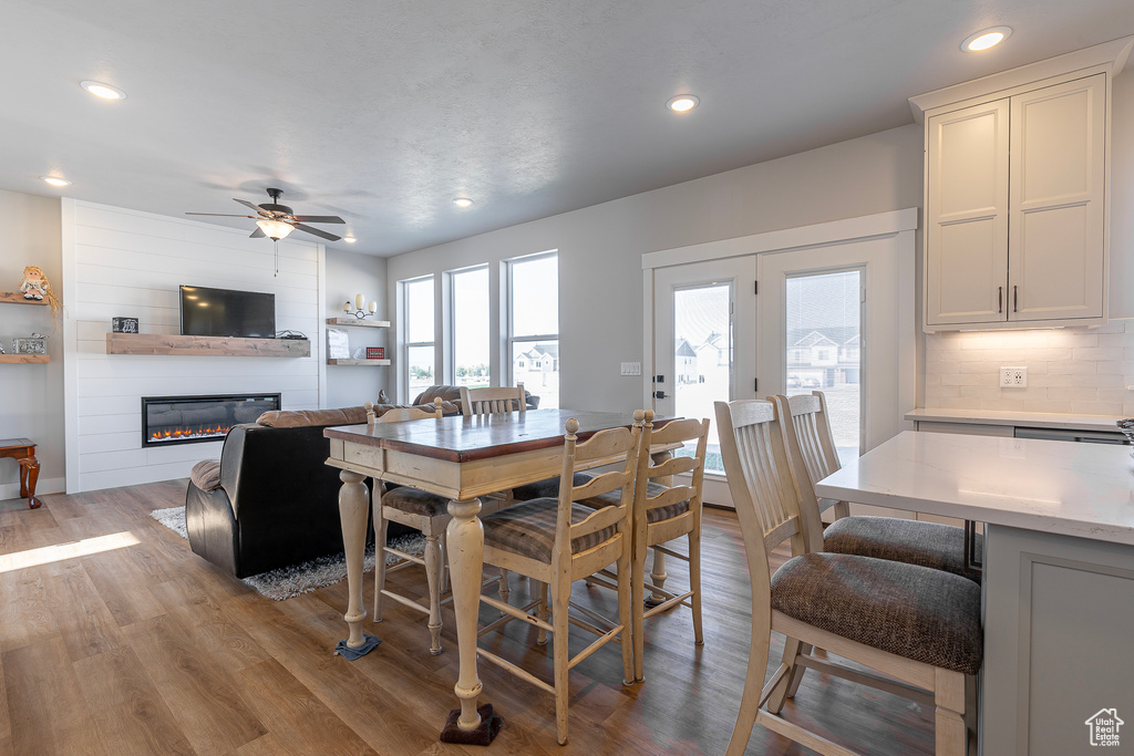 Dining area with a large fireplace, light wood-type flooring, and ceiling fan