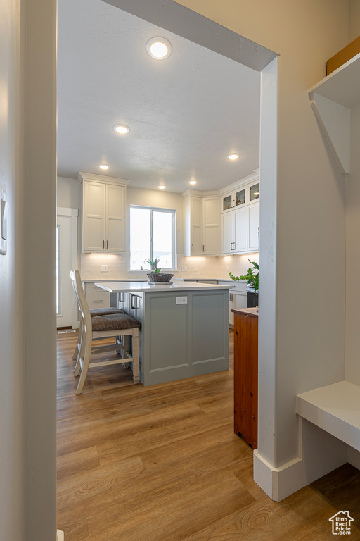 Kitchen featuring a breakfast bar area, a kitchen island, white cabinetry, and light hardwood / wood-style floors