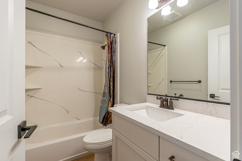 Full bathroom featuring vanity, toilet, and shower / bathtub combination with curtain