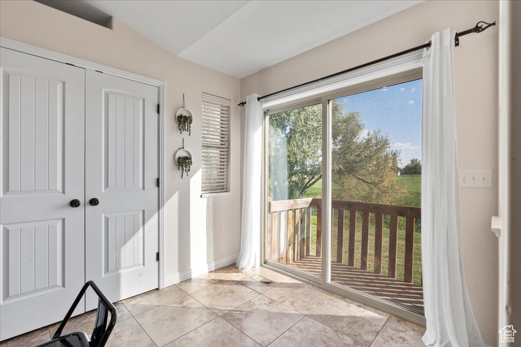 Doorway to outside featuring vaulted ceiling and light tile patterned flooring