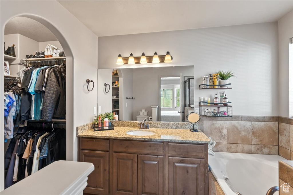 Bathroom with vanity and tiled tub