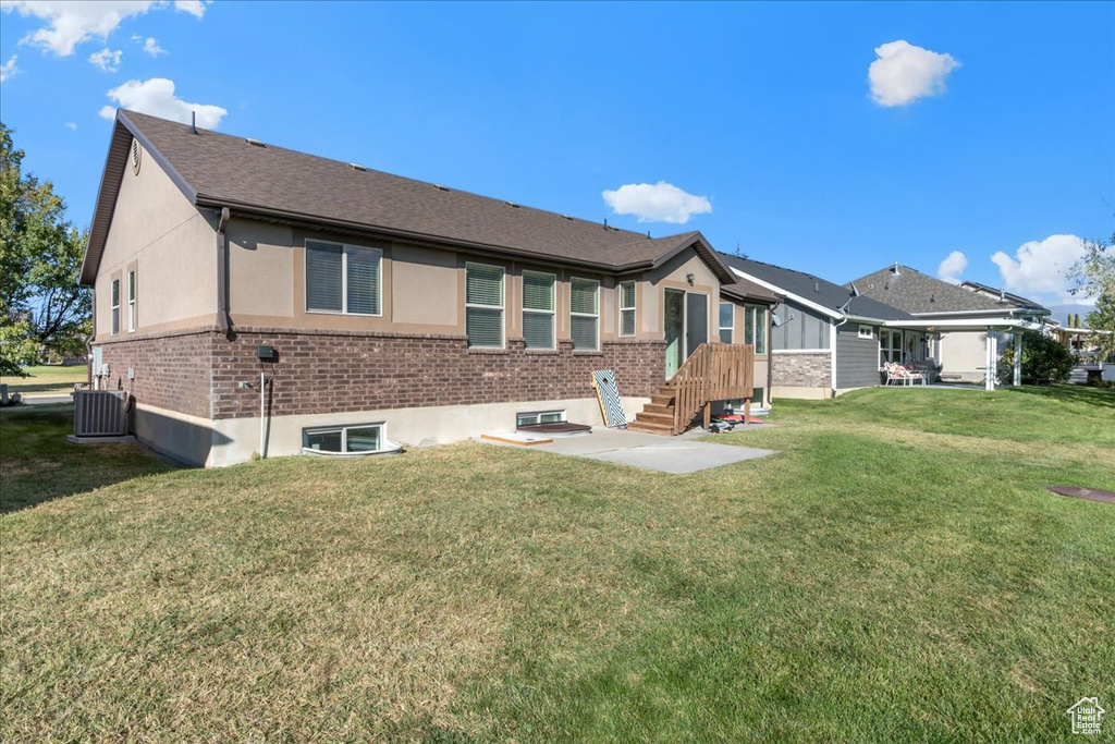 Rear view of property featuring cooling unit and a lawn