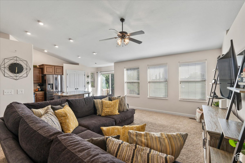 Carpeted living room featuring ceiling fan and vaulted ceiling