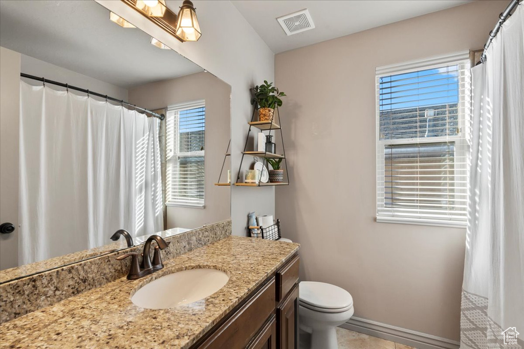 Bathroom featuring vanity, toilet, and tile patterned flooring