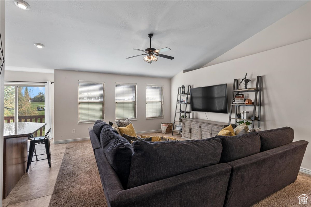 Living room featuring ceiling fan, lofted ceiling, and light tile patterned floors