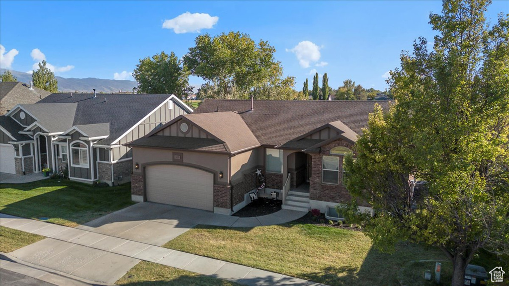 Craftsman-style home featuring a mountain view, a front lawn, and a garage