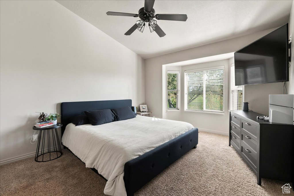 Carpeted bedroom with vaulted ceiling and ceiling fan