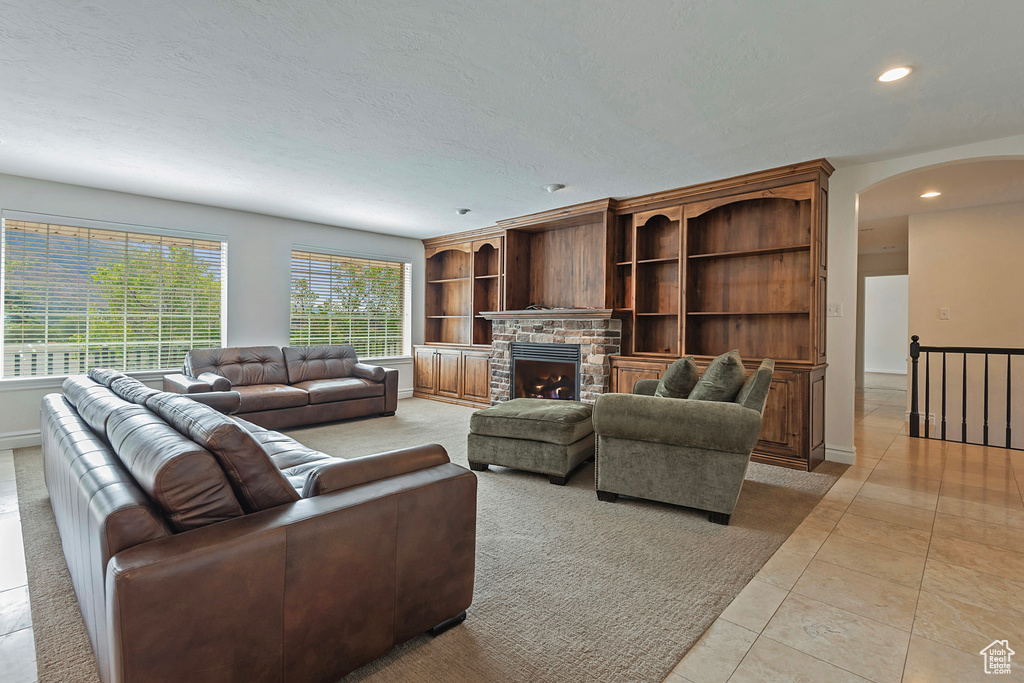 Living room featuring a textured ceiling, a fireplace, and light tile patterned floors