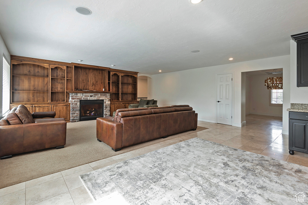 Tiled living room featuring a stone fireplace