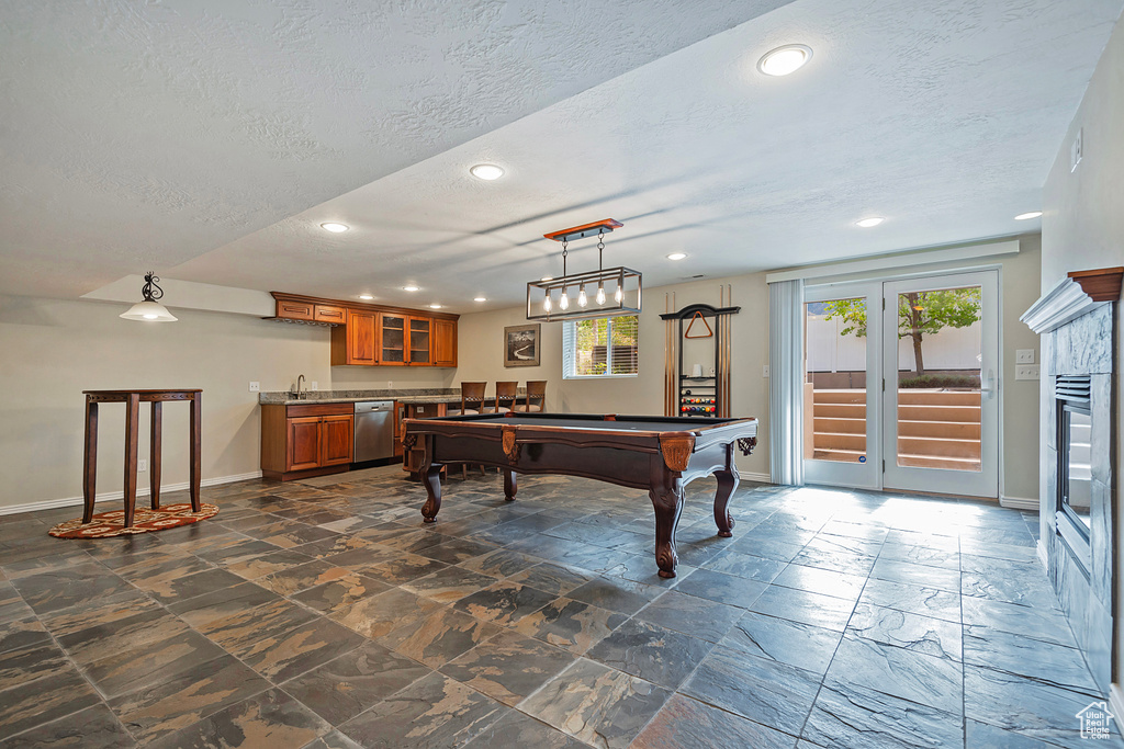 Playroom with indoor wet bar, billiards, a textured ceiling, and a healthy amount of sunlight