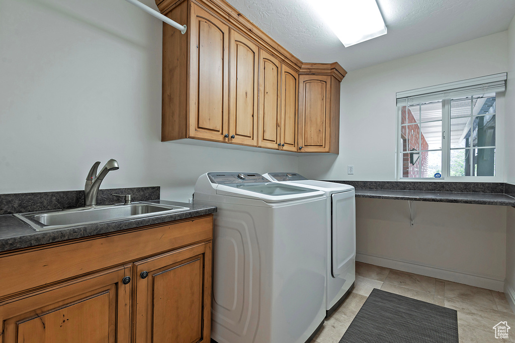 Clothes washing area with washer and dryer, cabinets, and sink