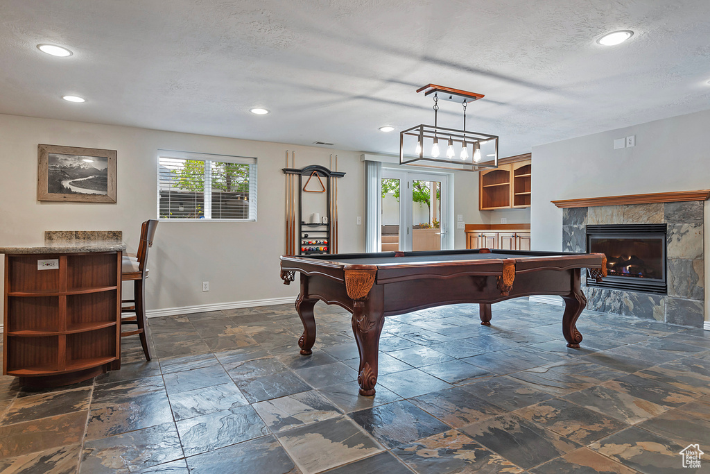 Playroom with a textured ceiling, billiards, and a tile fireplace