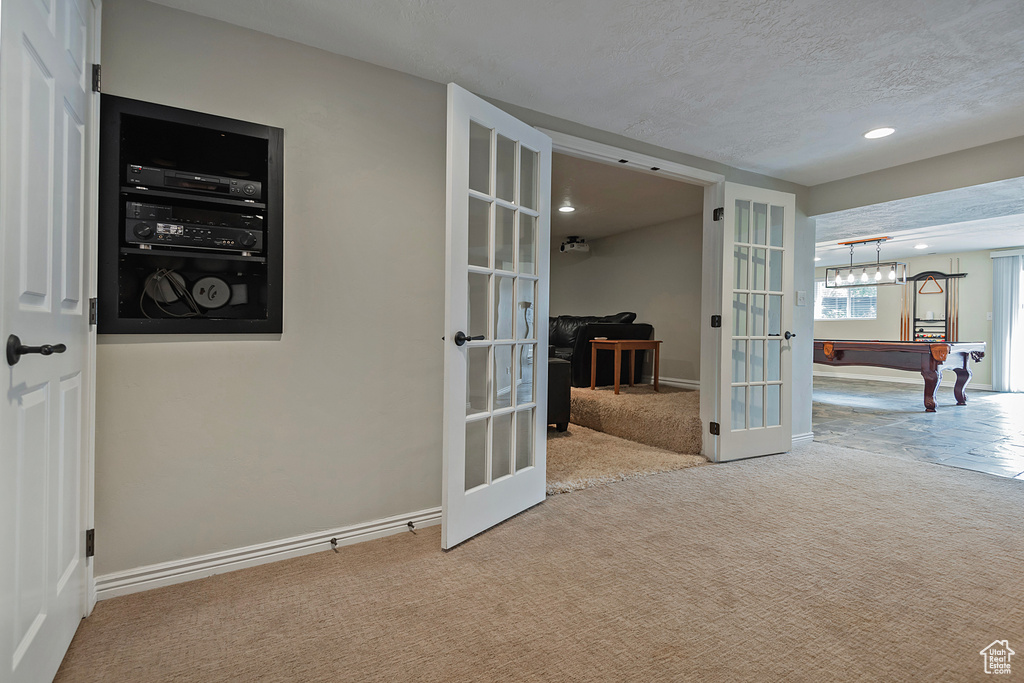 Interior space with french doors, light carpet, a textured ceiling, and pool table