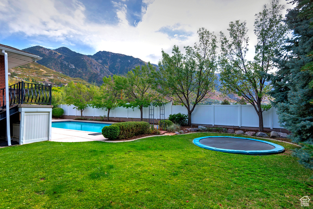 View of swimming pool featuring a trampoline, a yard, and a mountain view