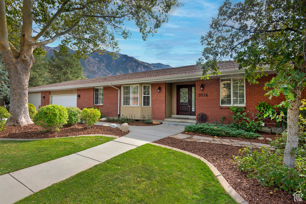 Ranch-style home with a mountain view, a front lawn, and a garage