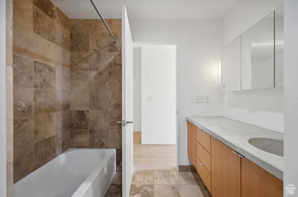 Bathroom featuring tiled shower / bath, vanity, and hardwood / wood-style floors