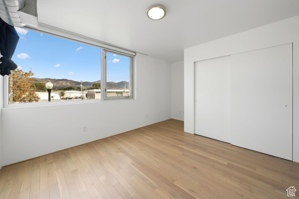 Unfurnished bedroom featuring light hardwood / wood-style floors, a closet, and a mountain view