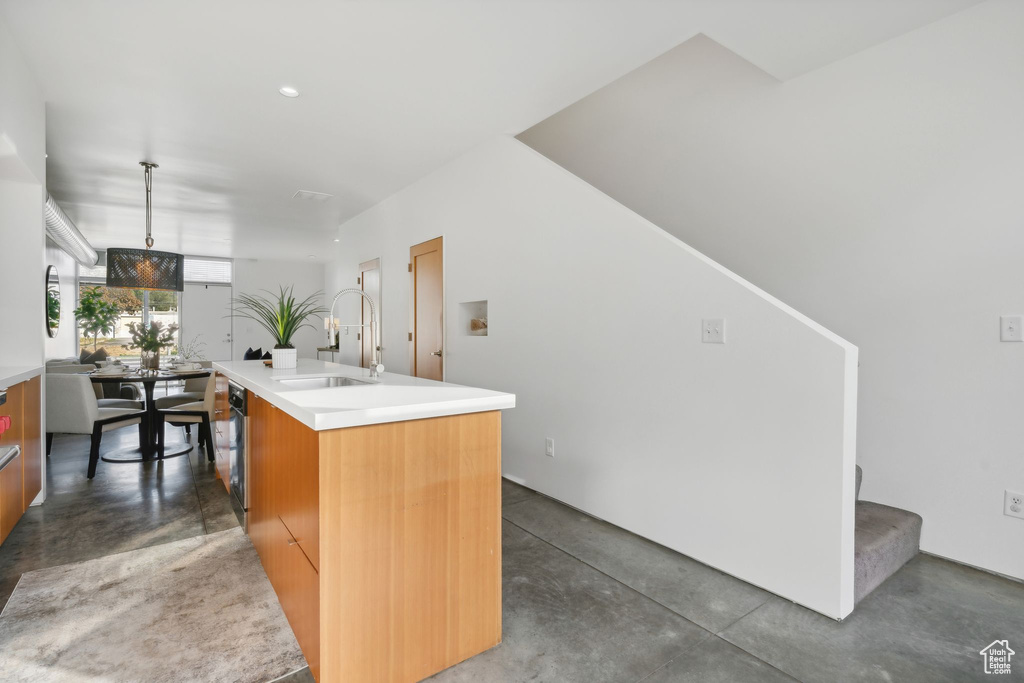 Kitchen with decorative light fixtures, sink, and a center island with sink