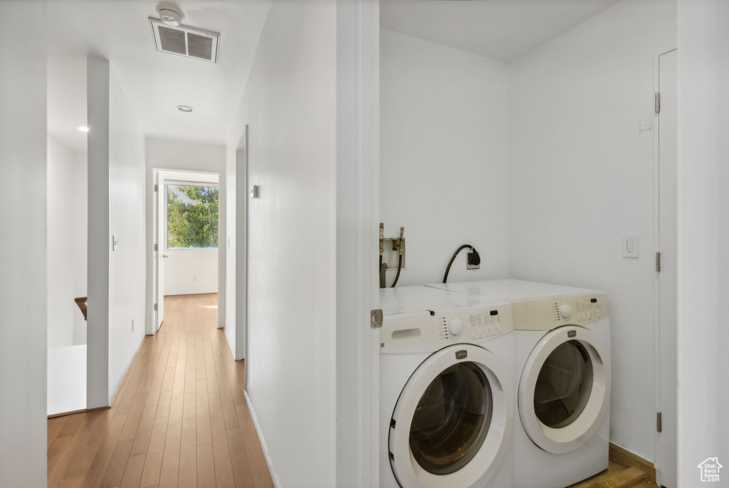 Washroom featuring light hardwood / wood-style flooring and washing machine and clothes dryer