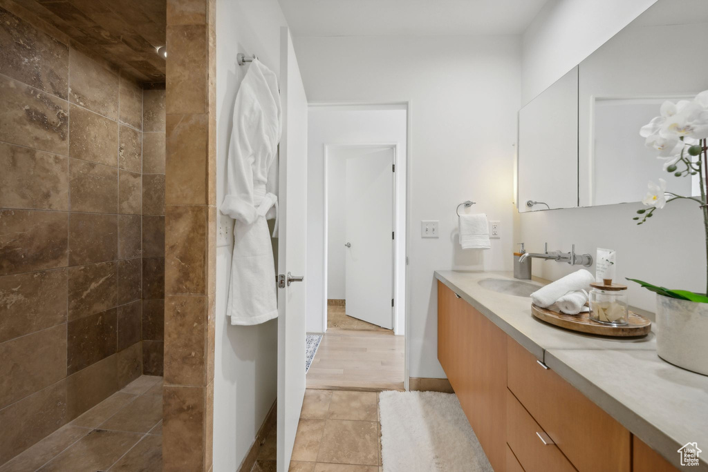 Bathroom with vanity, hardwood / wood-style floors, and a tile shower