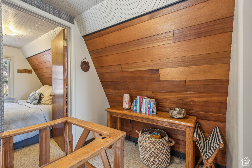 Carpeted bedroom with wood walls and vaulted ceiling