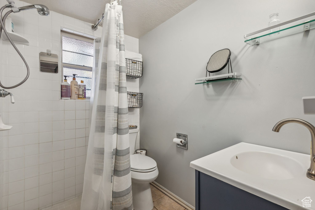 Bathroom featuring a textured ceiling, toilet, vanity, curtained shower, and tile patterned flooring