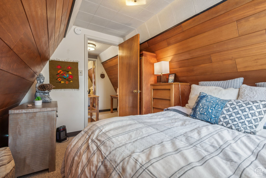 Carpeted bedroom featuring wooden walls