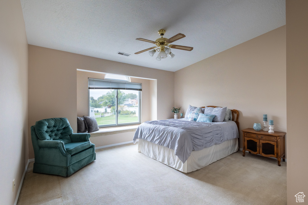 Carpeted bedroom with a textured ceiling and ceiling fan