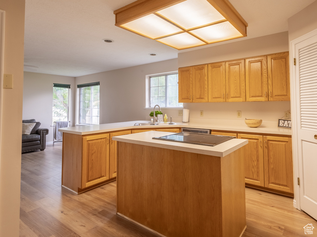 Kitchen with light hardwood / wood-style floors, kitchen peninsula, white fridge, and a center island