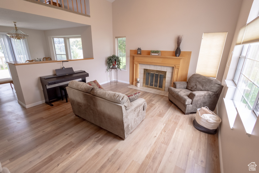 Living room featuring a tiled fireplace, a high ceiling, and light wood-type flooring