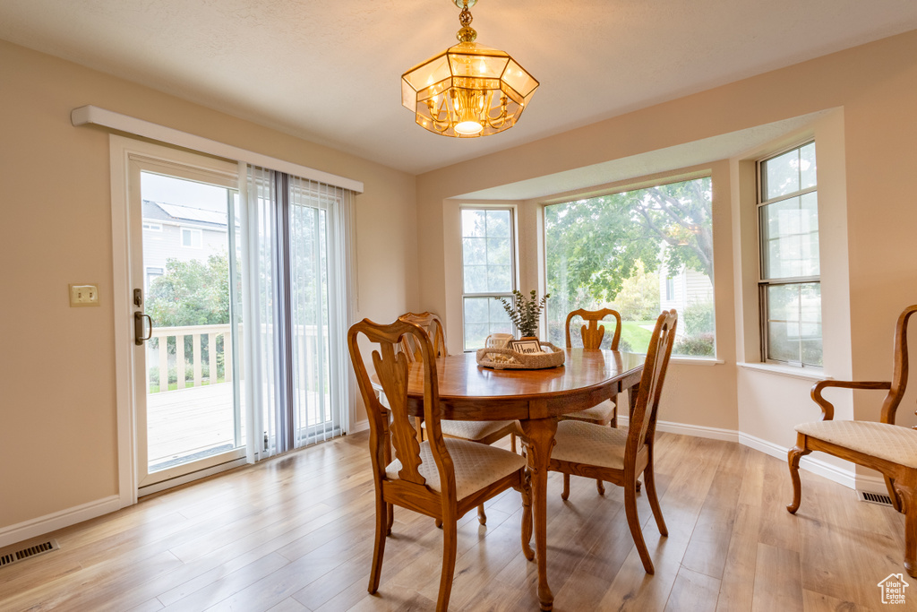 Dining space with a wealth of natural light, a chandelier, and light hardwood / wood-style floors