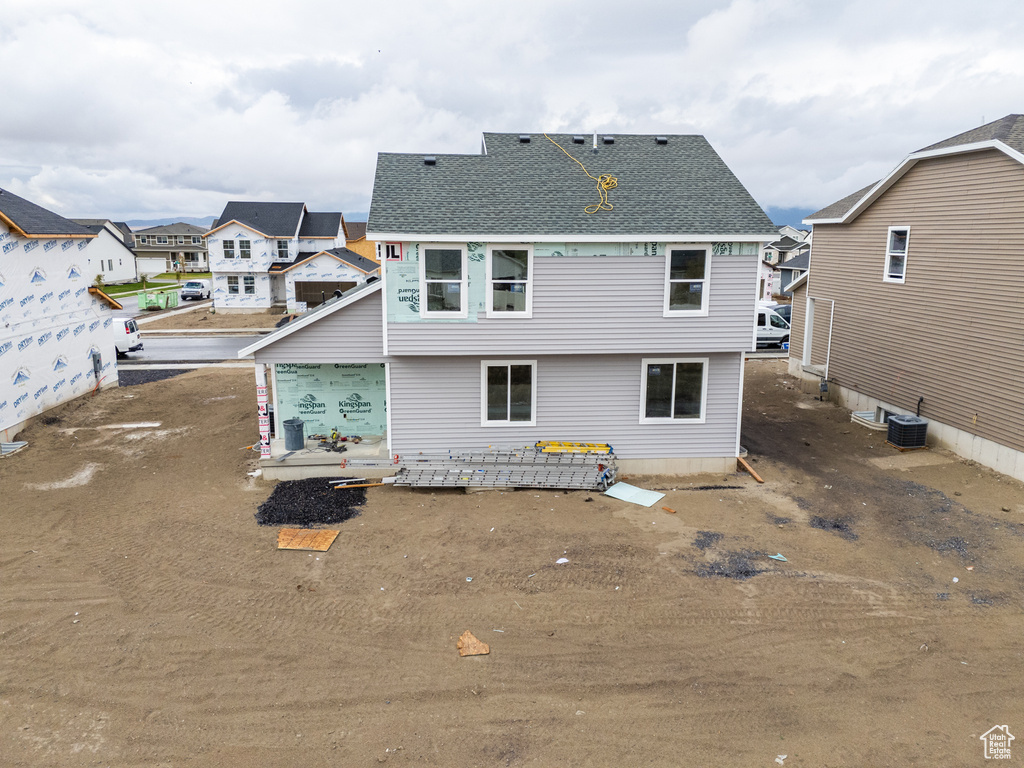 Back of property with central air condition unit and a garage