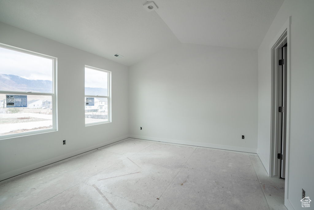 Spare room with a mountain view and lofted ceiling