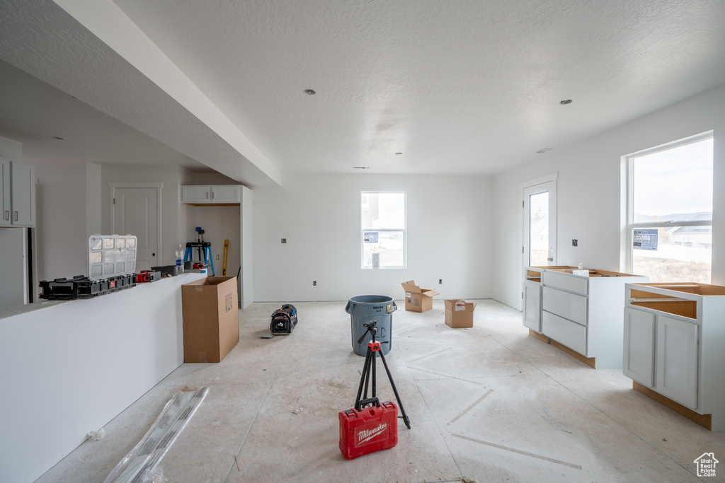 Kitchen featuring white fridge, a textured ceiling, and white cabinetry