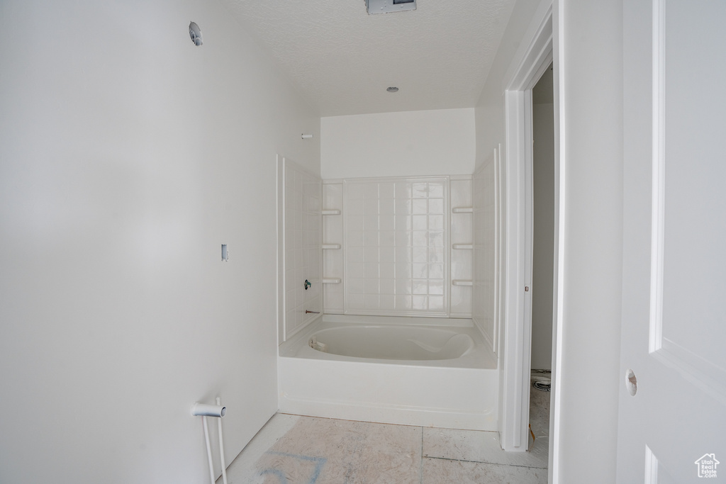 Bathroom with a textured ceiling and shower / bathtub combination