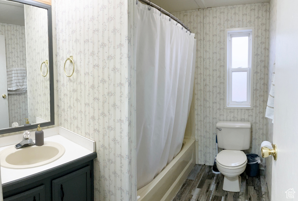 Full bathroom featuring toilet, shower / tub combo with curtain, vanity, and hardwood / wood-style flooring