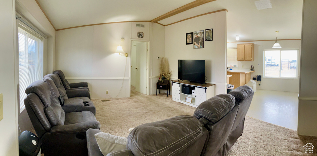 Living room with ornamental molding, vaulted ceiling, and light colored carpet