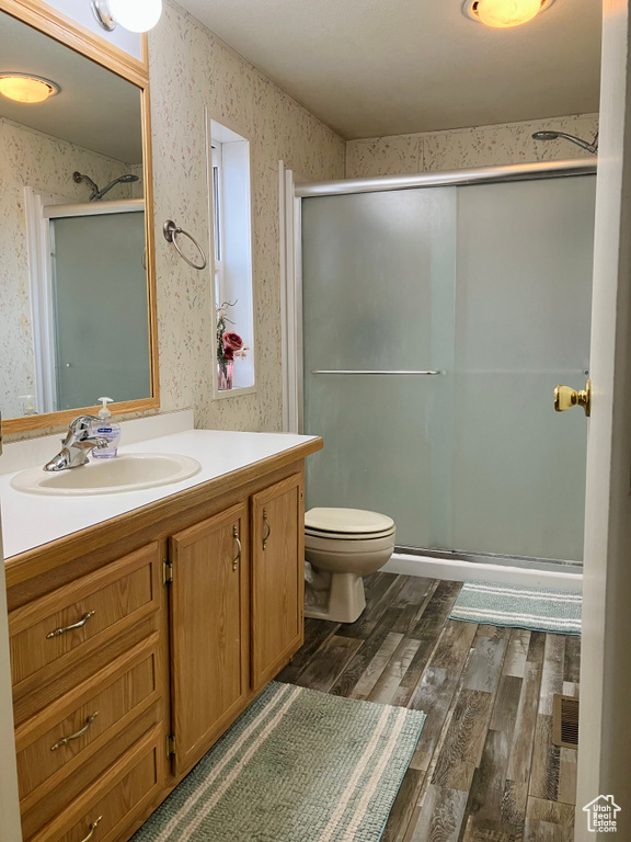 Bathroom featuring vanity, hardwood / wood-style floors, and a shower with shower door